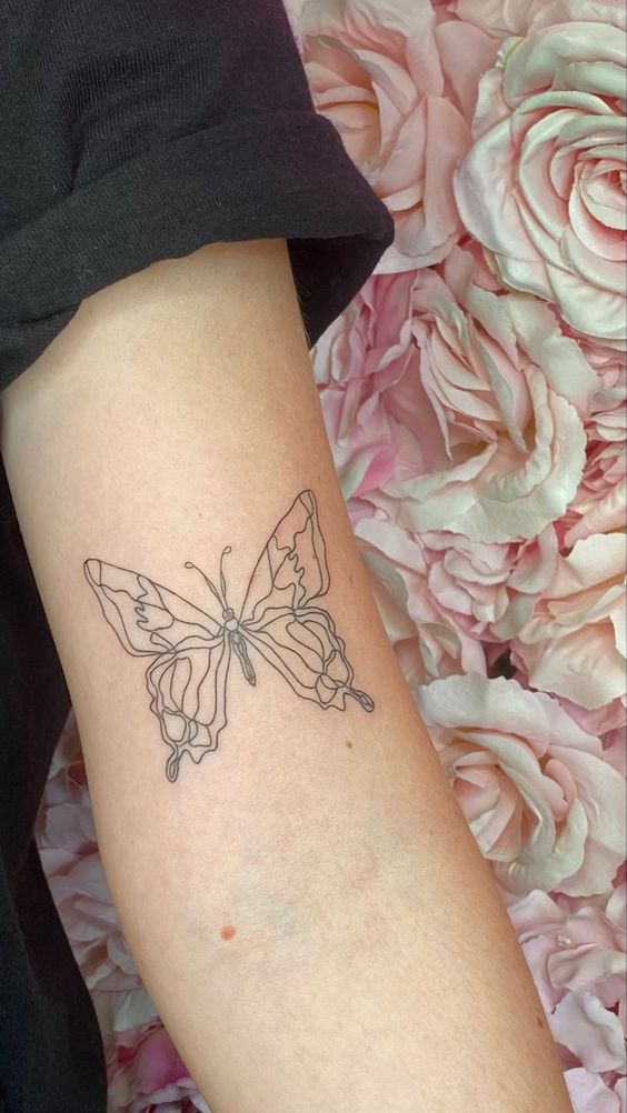 Minimalistyczny tatuaż motylkowy na przedramieniu
